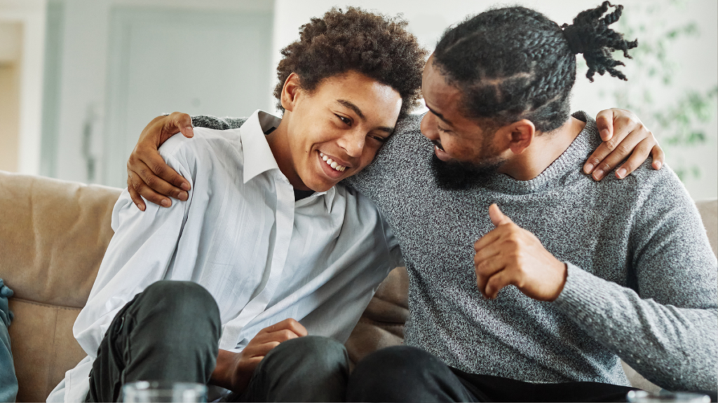 young man and father sitting together talking